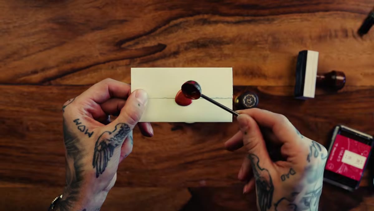 Wax seal being pressed onto journal page beside stamped entries
